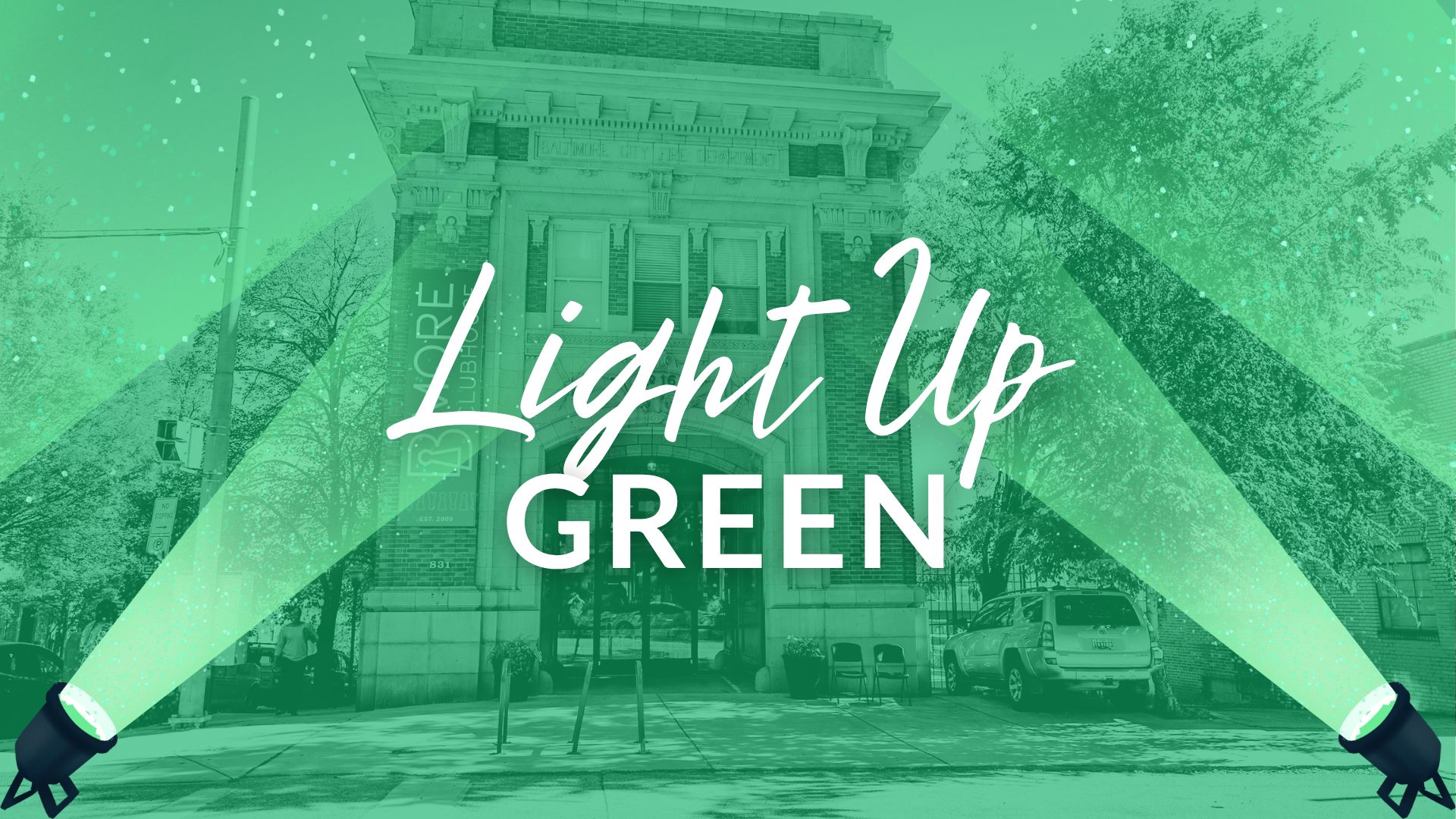 An image featuring a building illuminated by green lights, with the text "Light Up GREEN" prominently displayed.
